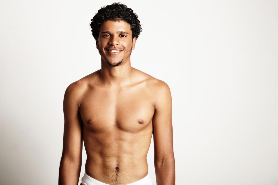 Free Image of young smiling shirtless man on a white wall 