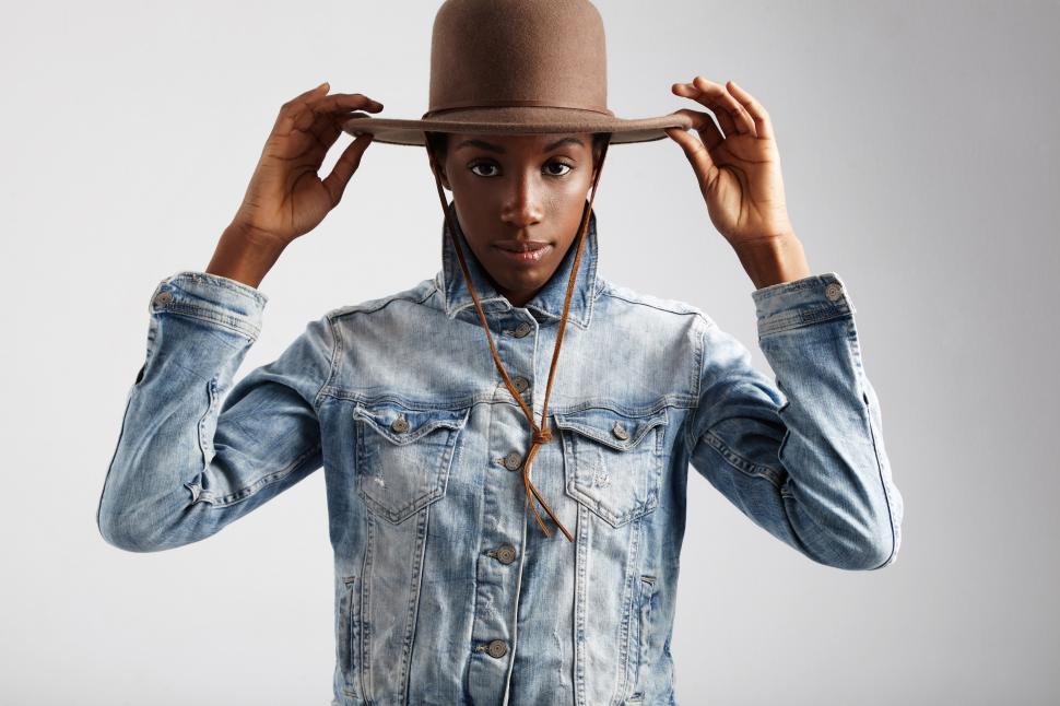Free Image of black woman in denim jacket puts wide brimmed hat on 