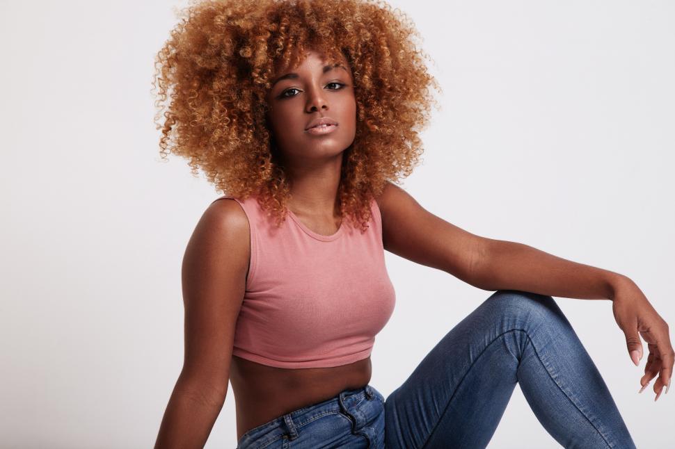 Free Image of Black woman with big afro hair in studio shoot arm on bent leg 