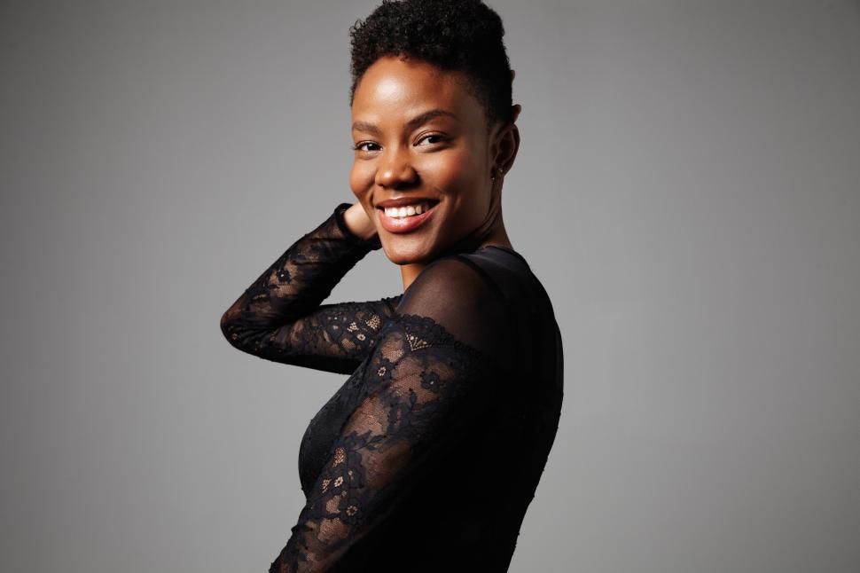 Free Image of happy smiling black woman turned sideways to camera touches her short hair 