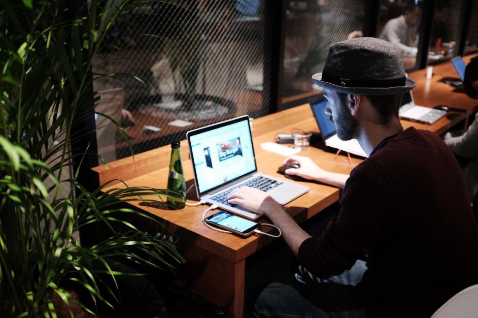 Free Image of A man sitting at a desk with a laptop and a phone 