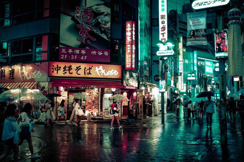 Free Image of People walking on a wet street with signs and people walking 