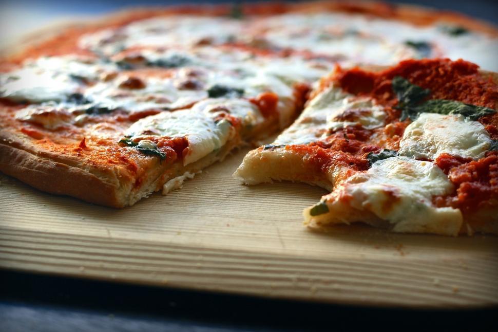 Free Image of A pizza with a bite taken out of it 