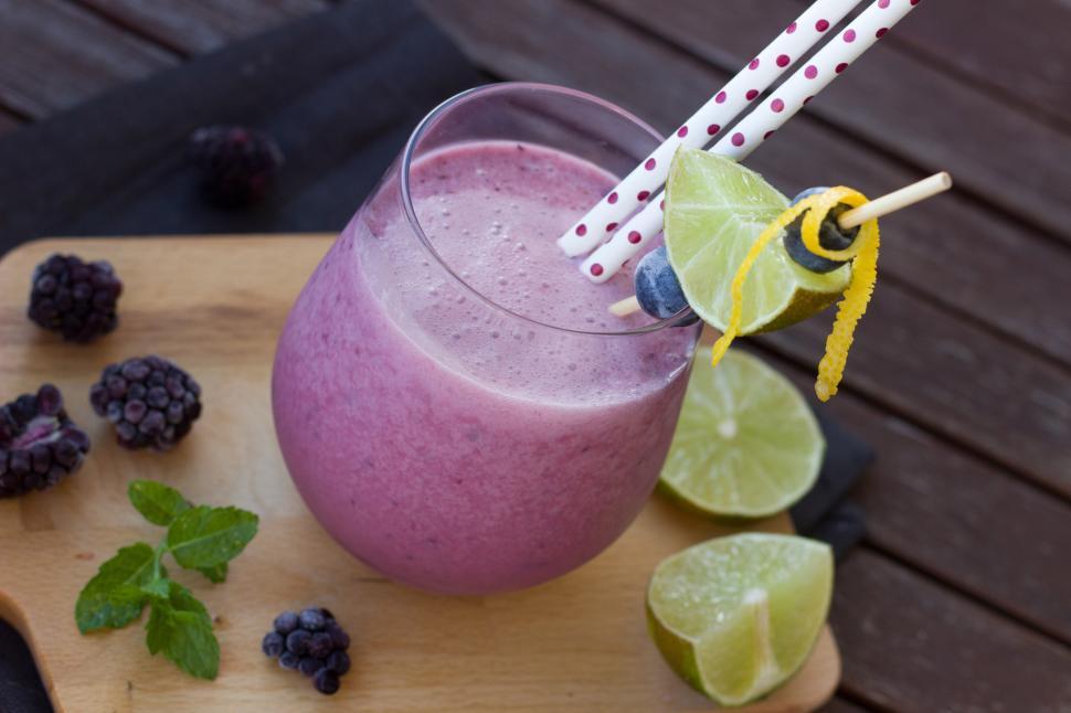 Free Image of A glass of purple smoothie with straws and limes 