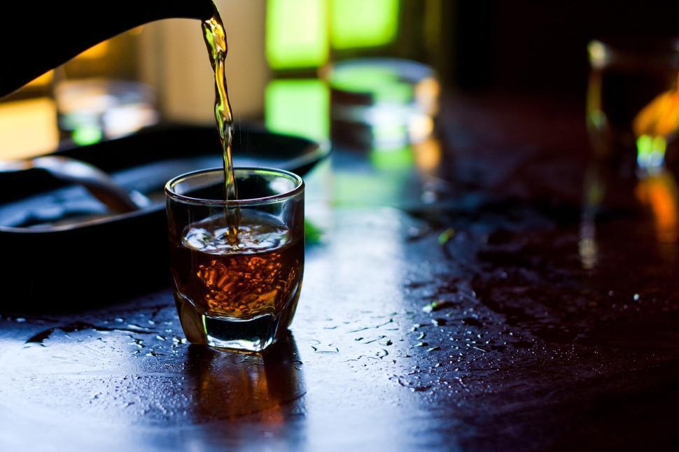 Free Image of A glass of brown liquid being poured into a glass 