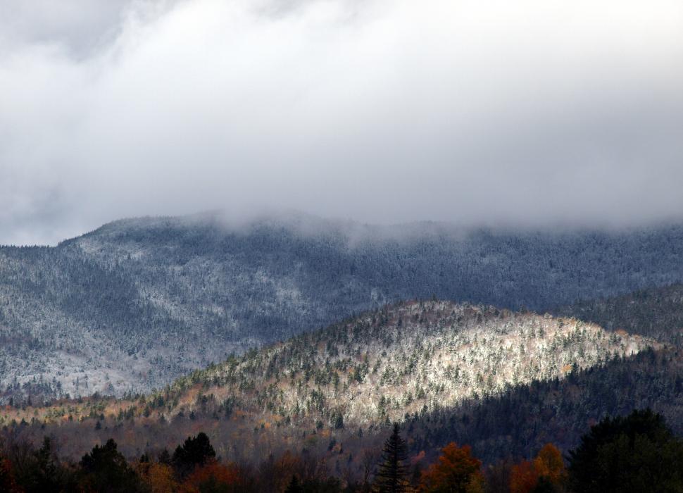 Free Image of A mountain range with trees and clouds 