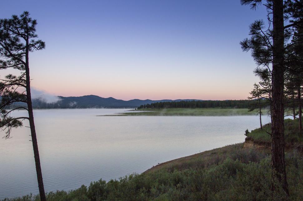 Free Image of A body of water with trees and mountains in the background 