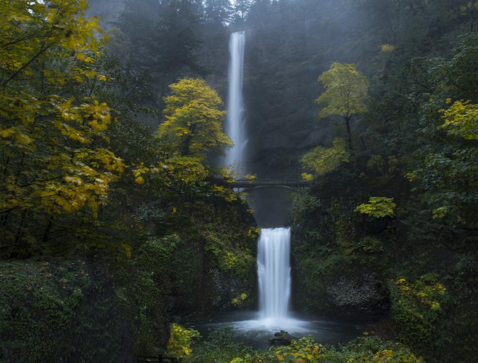 Free Image of A waterfall with a bridge over it 