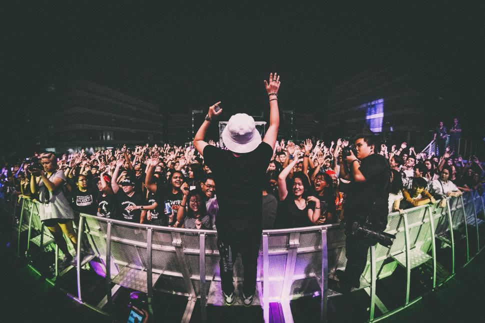 Free Image of A person standing on a stage with a crowd of people 