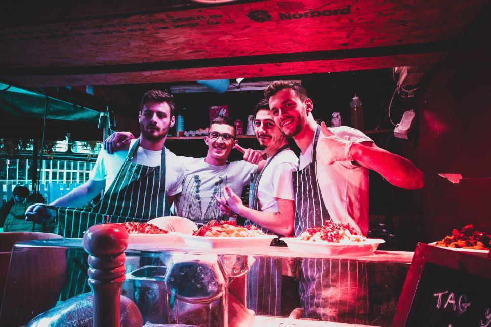 Free Image of A group of men standing in front of a counter with food 