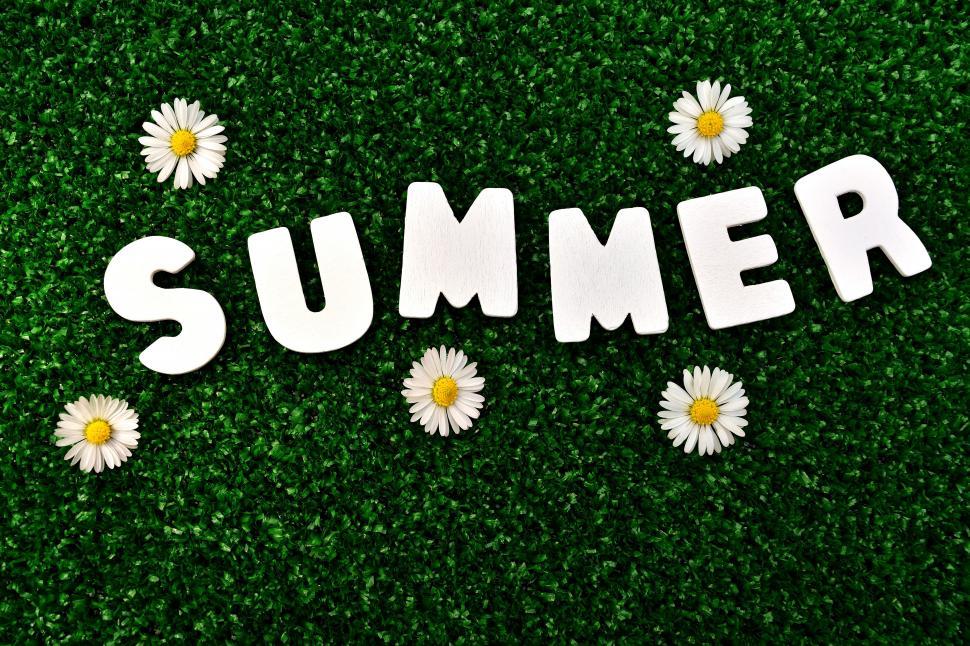 Free Image of White letters on a green surface with white flowers 