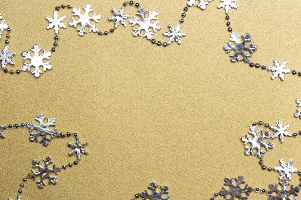 Free Image of A silver snowflakes and beads on a gold background 