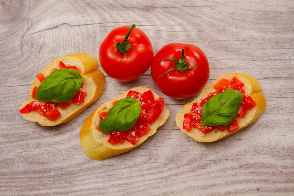 Free Image of A group of tomatoes and bread with basil on top 