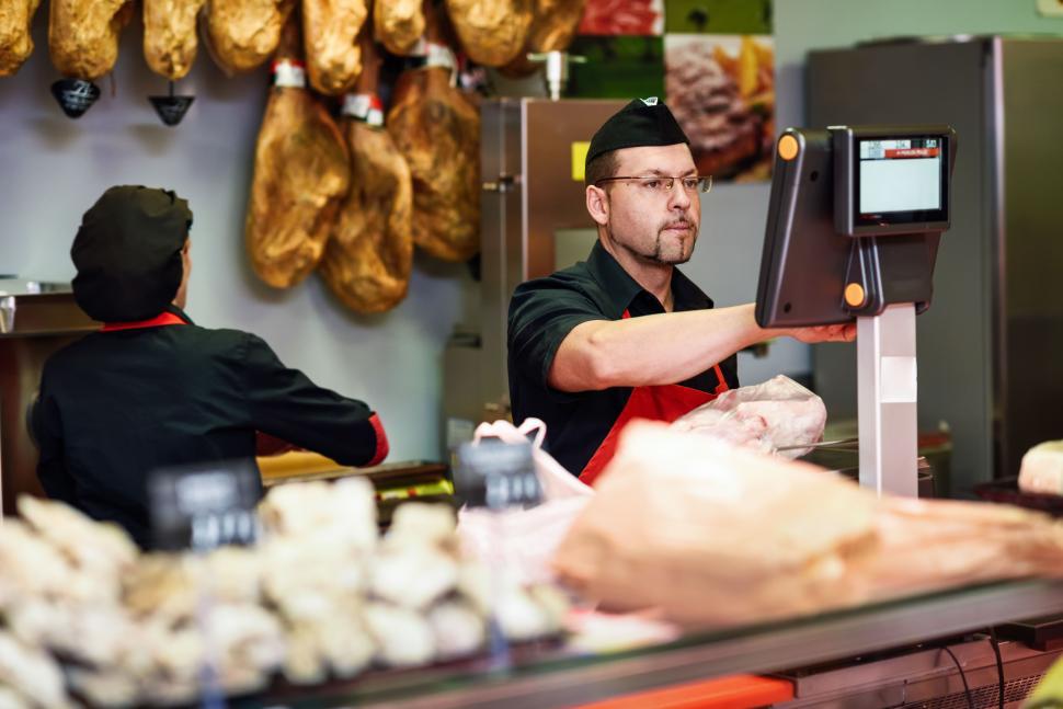 Free Image of Butcher in a butcher s shop weighing the meat and charging 