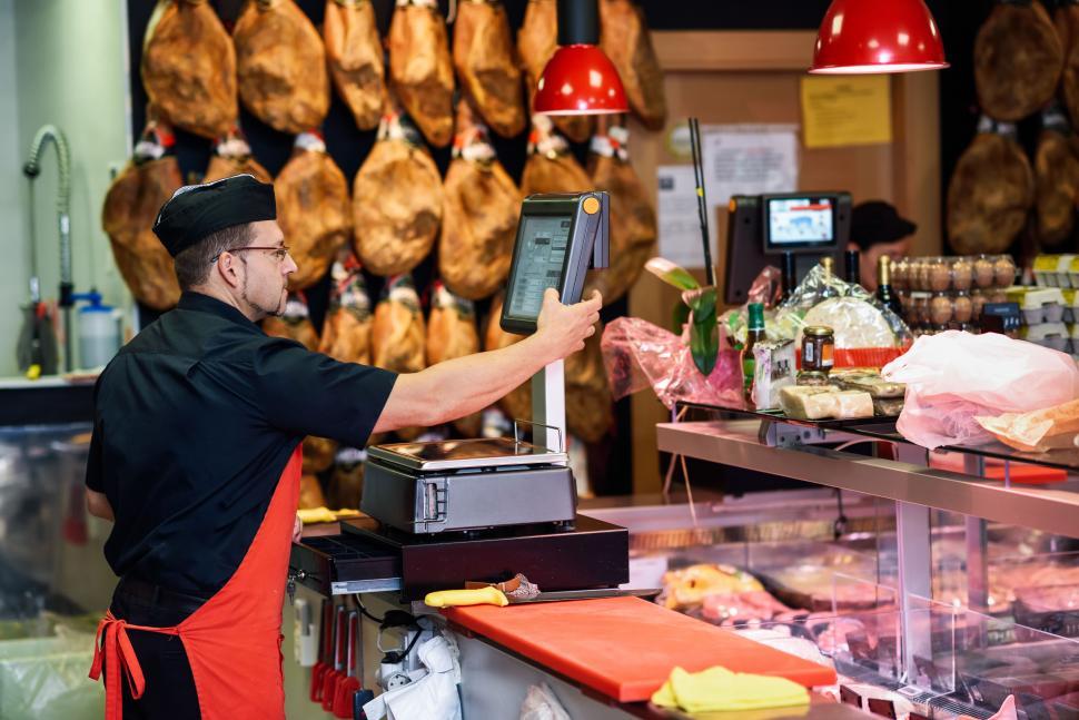 Free Image of Butcher in a butcher s shop weighing the meat and charging 