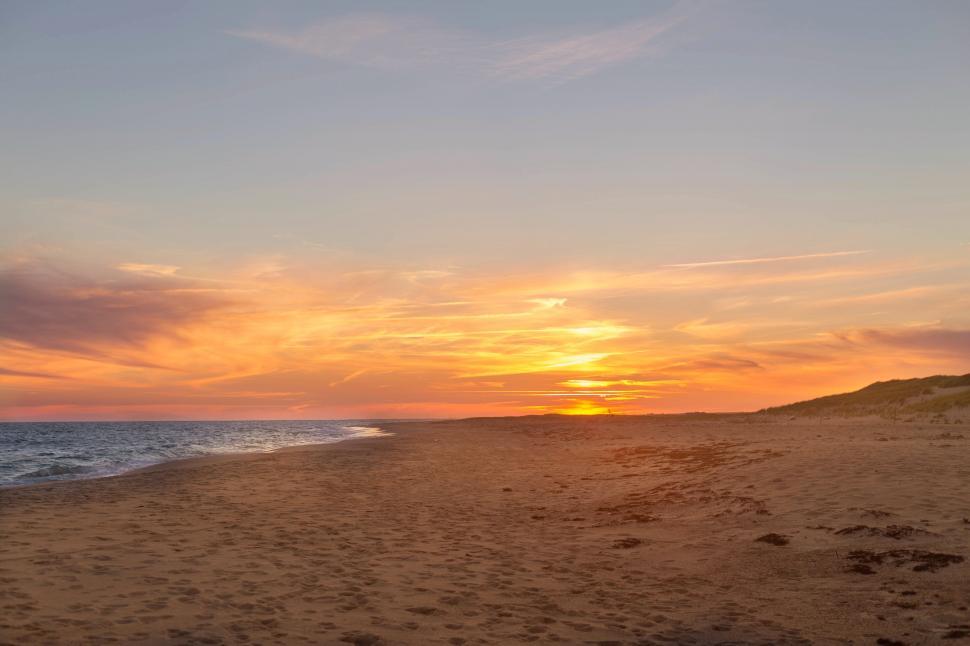 Free Image of A beach with a body of water and a sunset 