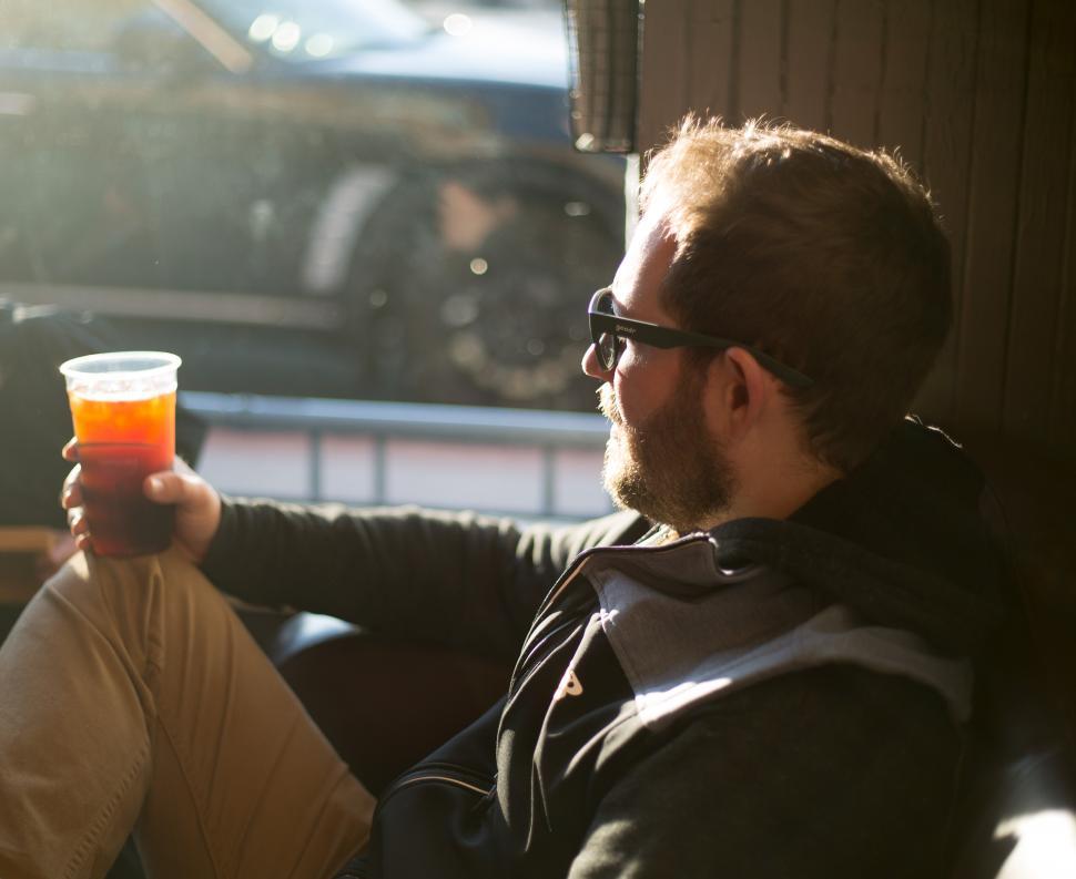 Free Image of A man sitting in a car holding a cup of liquid 