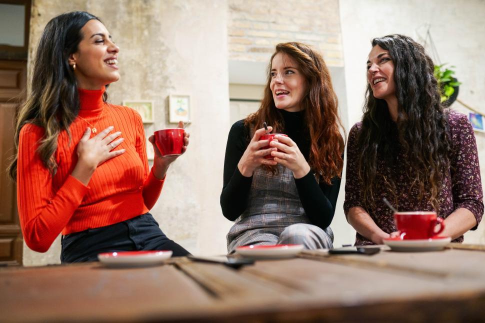 Free Image of Group of three happy friends drinking coffee in a cafe bar. 