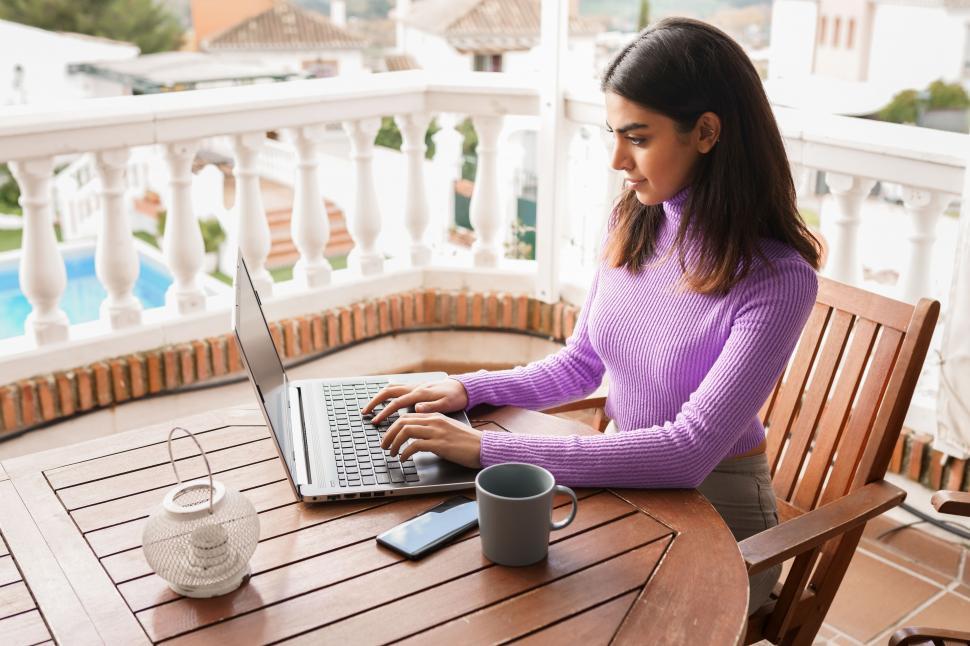 Free Image of Persian woman on her balcony using laptop computer 