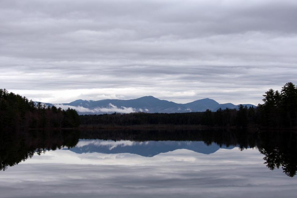Free Image of A body of water with trees and mountains in the background 