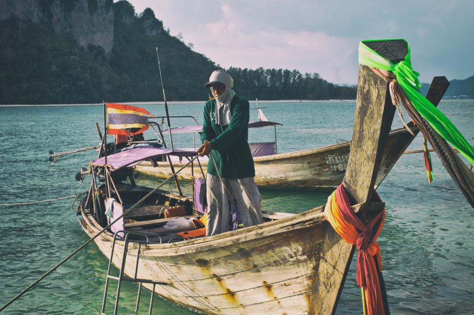 Free Image of A man standing on a boat in the water 