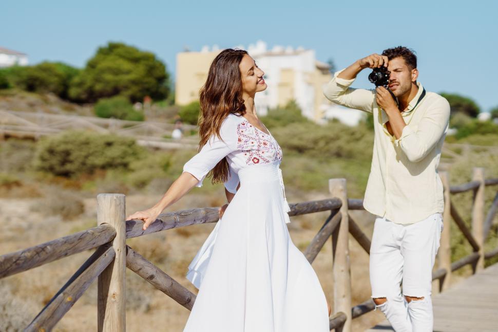 Free Image of Man photographing his girlfriend on a lovers  trip. 