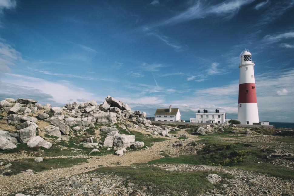 Free Image of A lighthouse with rocks and a building 