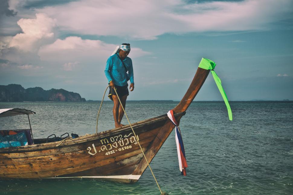 Free Image of A man standing on a boat in the water 