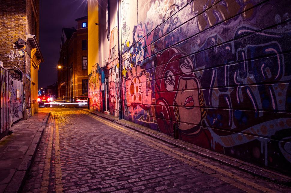 Free Image of A brick road with graffiti on the side of a building 