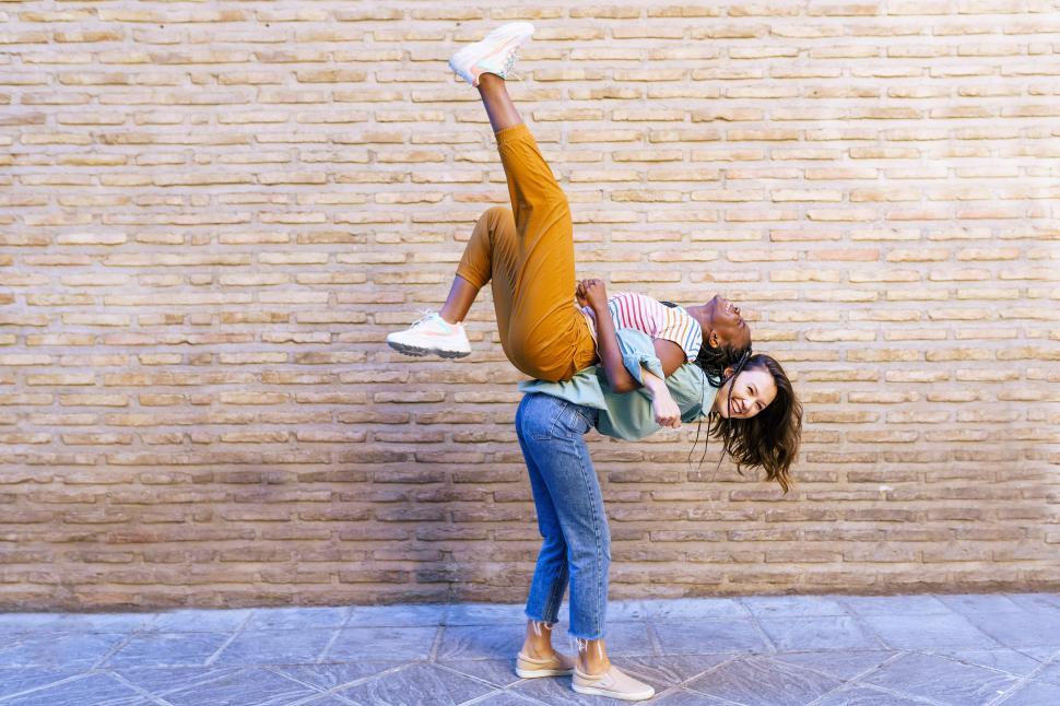 Free Image of Funny multiethnic woman carrying her best friend piggyback 