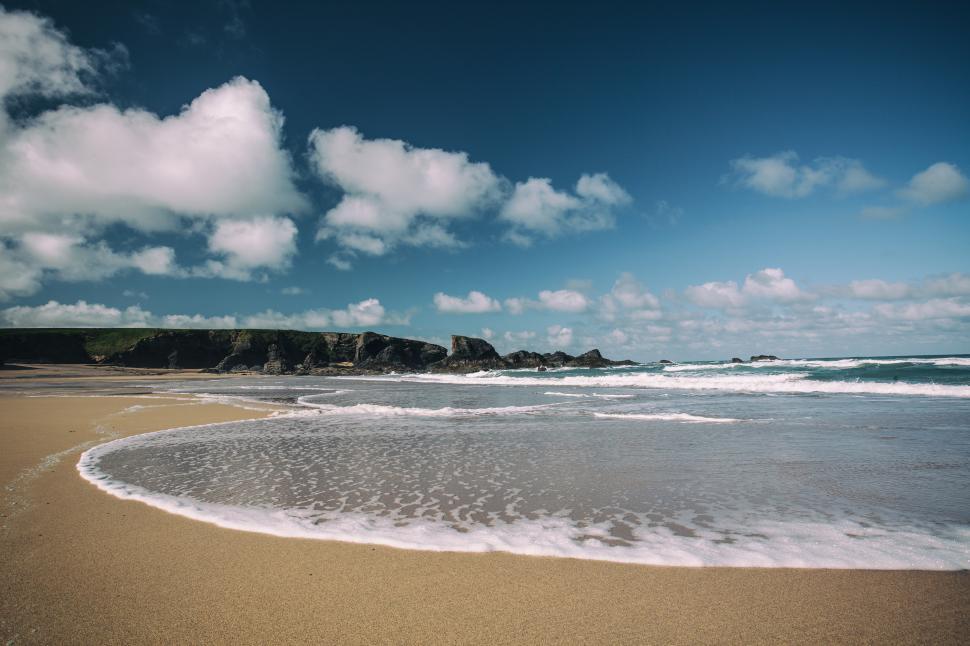 Free Image of A beach with waves and rocks 