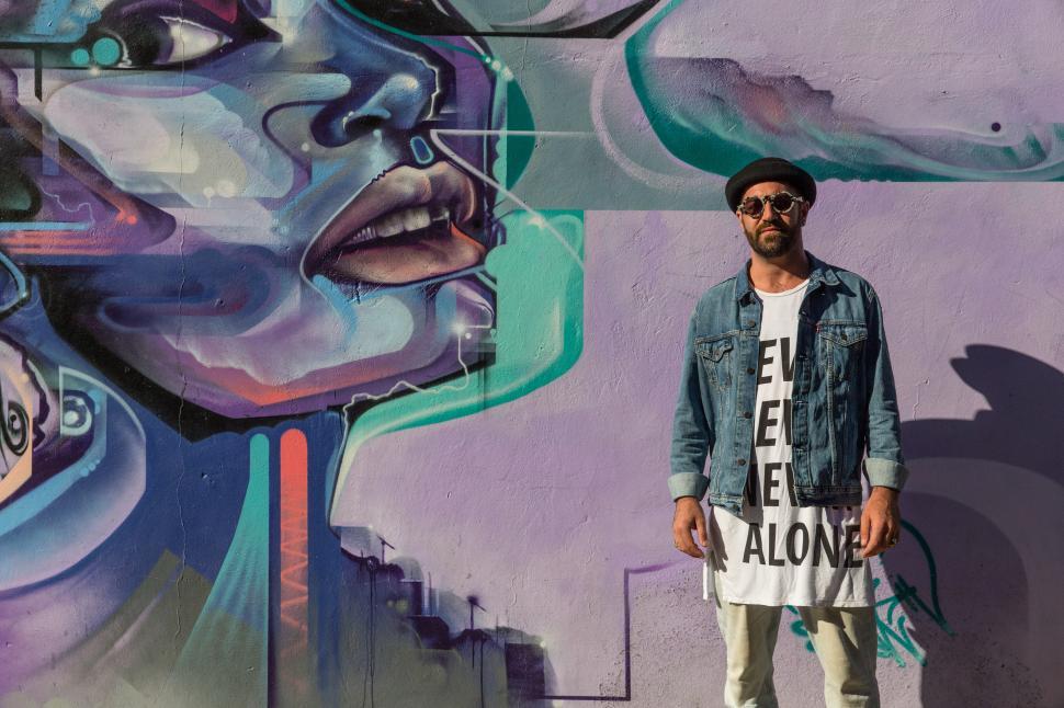 Free Image of A man standing in front of a mural 