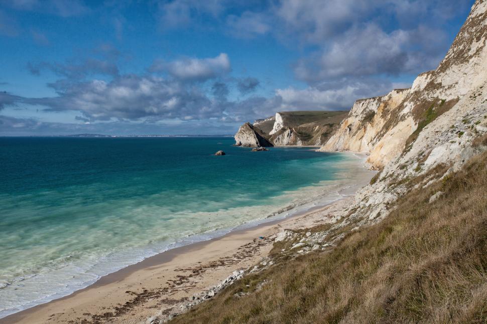 Free Image of A beach with a body of water and cliffs 