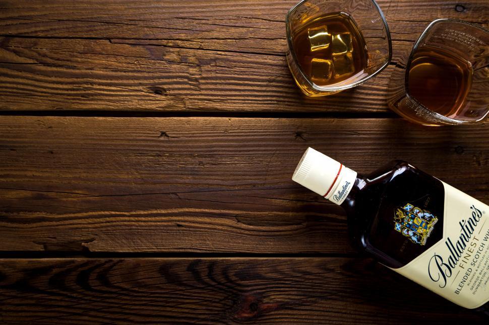 Free Image of A bottle of alcohol next to a glass of liquid 