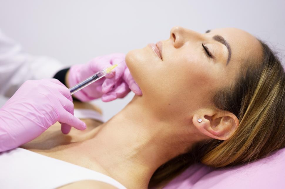 Free Image of Doctor injecting hyaluronic acid into the ching of a woman as a facial rejuvenation treatment. 