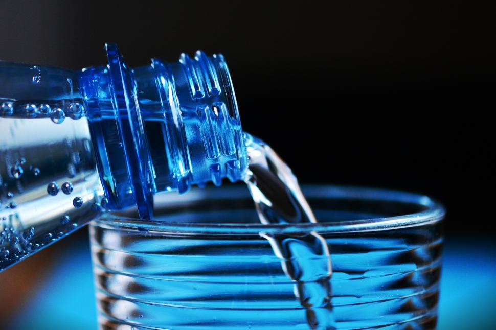 Free Image of A close up of a bottle pouring water into a glass 