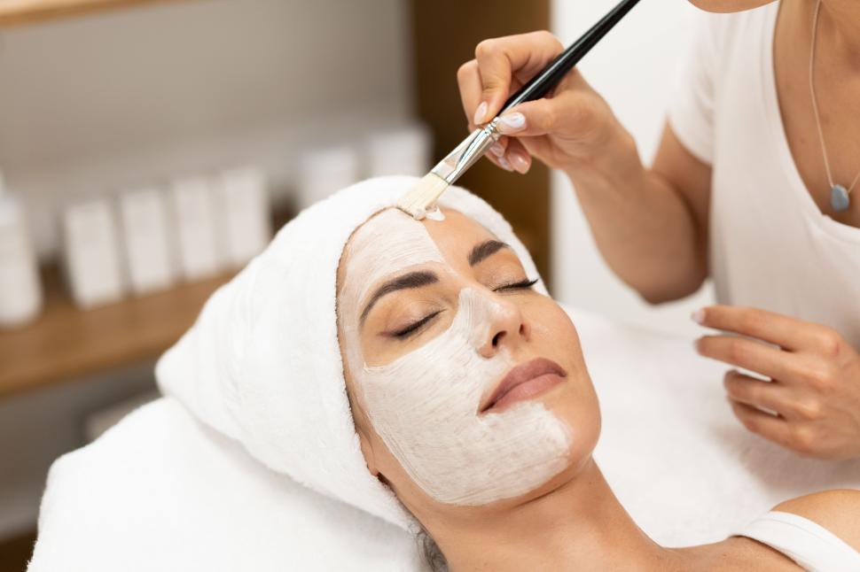 Free Image of Aesthetics applying a mask to the face of a Middle-aged woman in modern wellness center. 