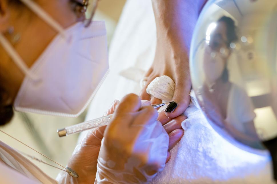 Free Image of Beautician giving a pedicure painting her client s nails in a beauty centre. 