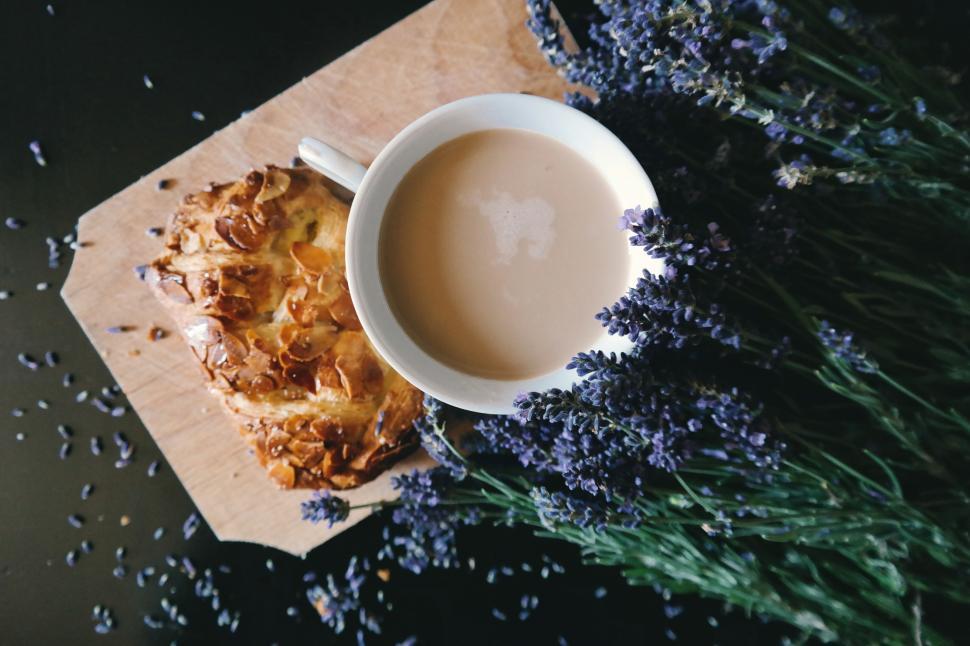 Free Image of A cup of coffee and a pastry on a cutting board 