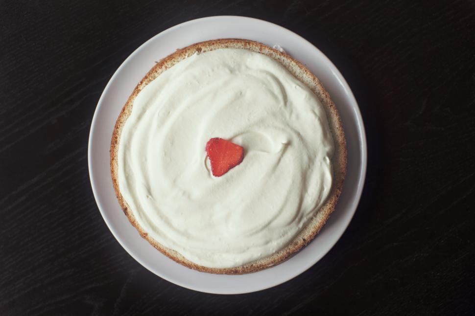 Free Image of A cake with whipped cream and a strawberry on top 