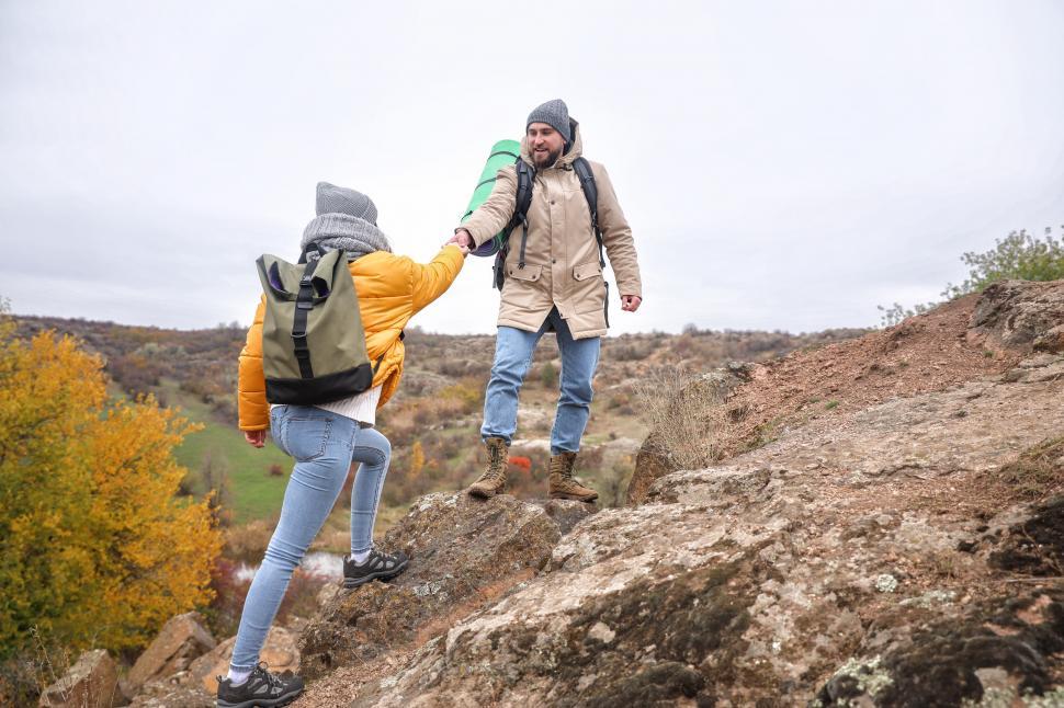 Free Image of A man and woman holding hands on a rocky hill 