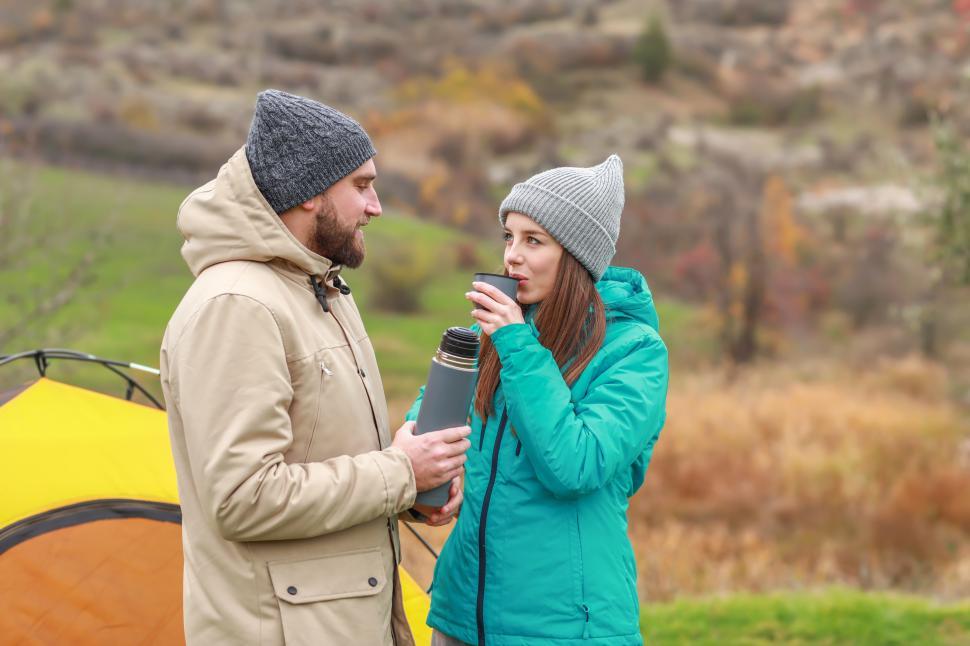 Free Image of A man and woman standing outside drinking from a thermos 