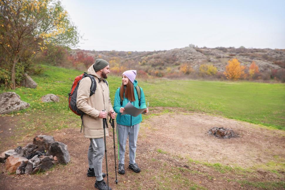 Free Image of A man and woman standing in a field with a map and poles 