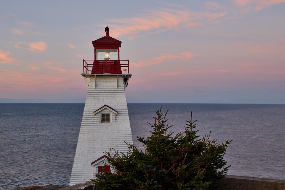 Free Image of A lighthouse with a tree in front of it 