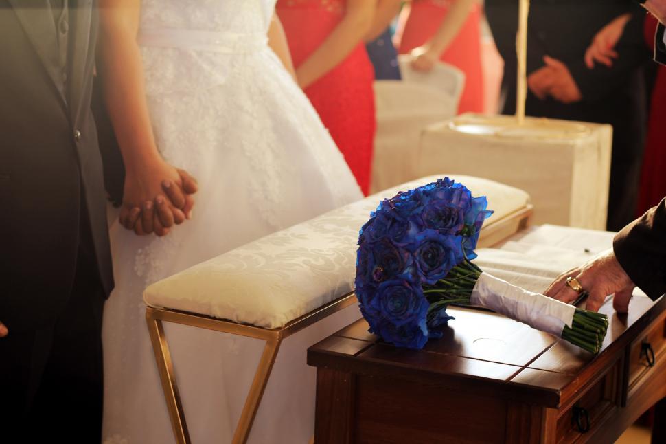Free Image of A bride in a white dress with a bouquet of blue roses 