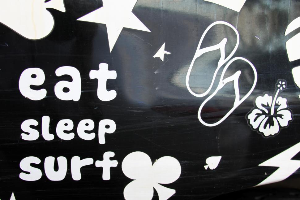 Free Image of A black sign with white text and flip flops 