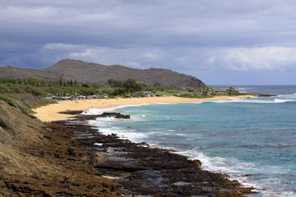 Free Image of A beach with rocky shore and mountains in the background 