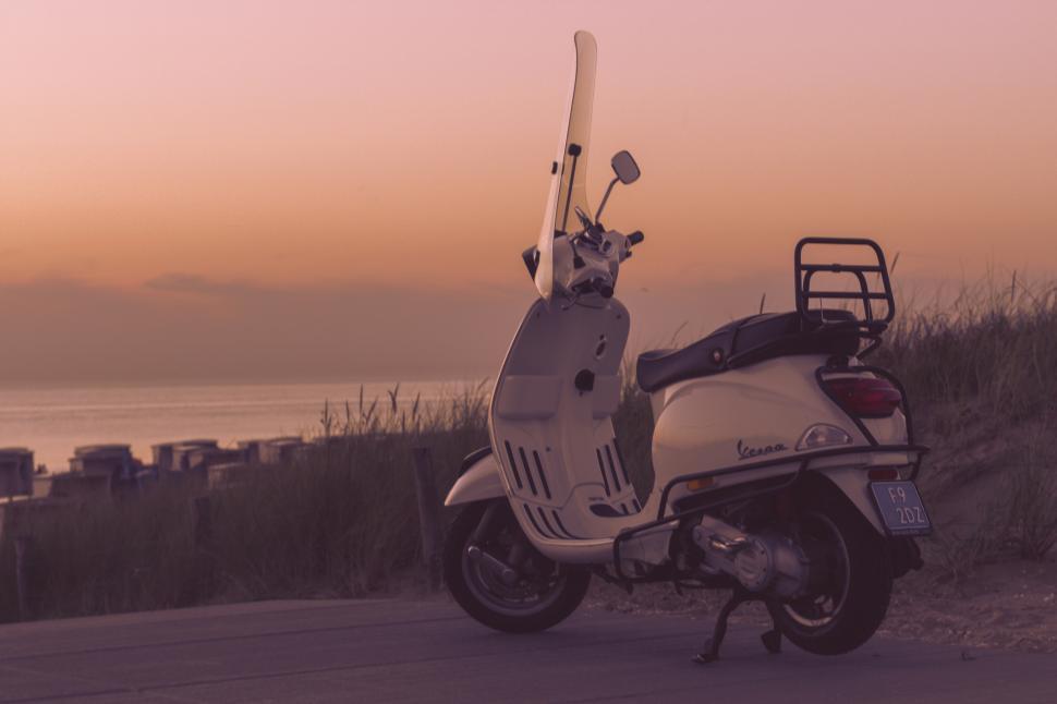 Free Image of A white scooter parked on a sidewalk 