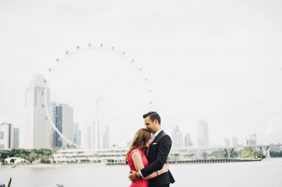 Free Image of A man and woman kissing in front of a ferris wheel 