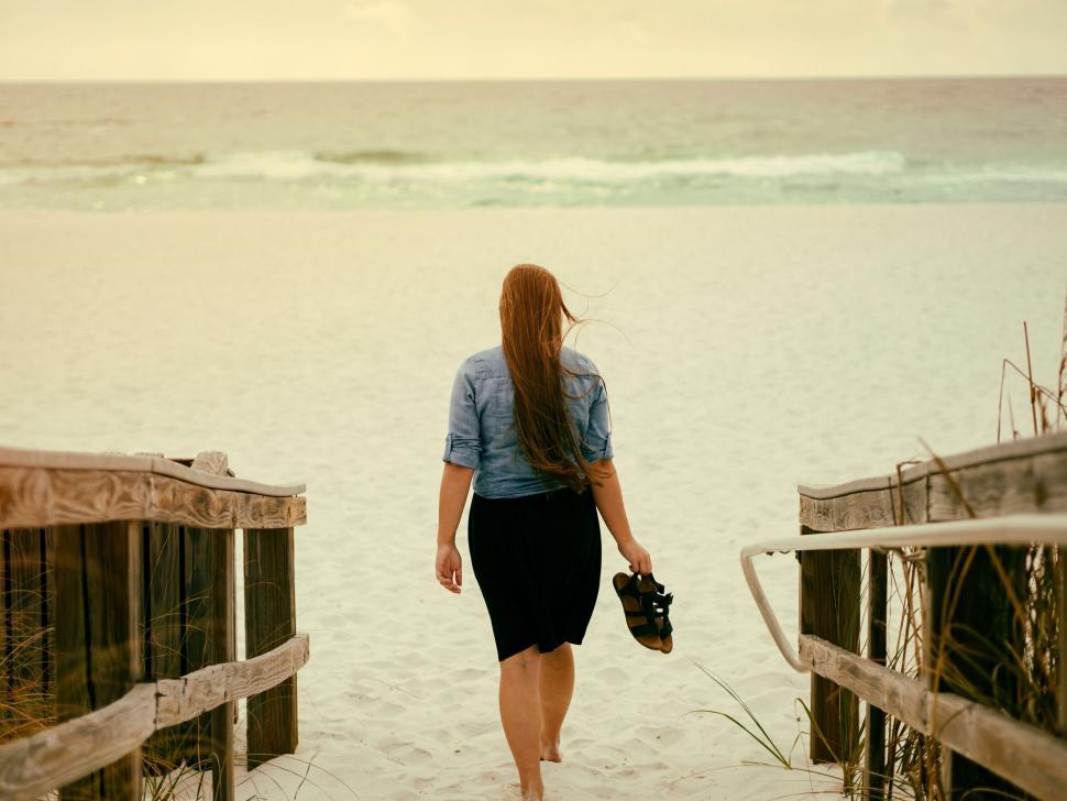 Free Image of A woman walking on a beach 